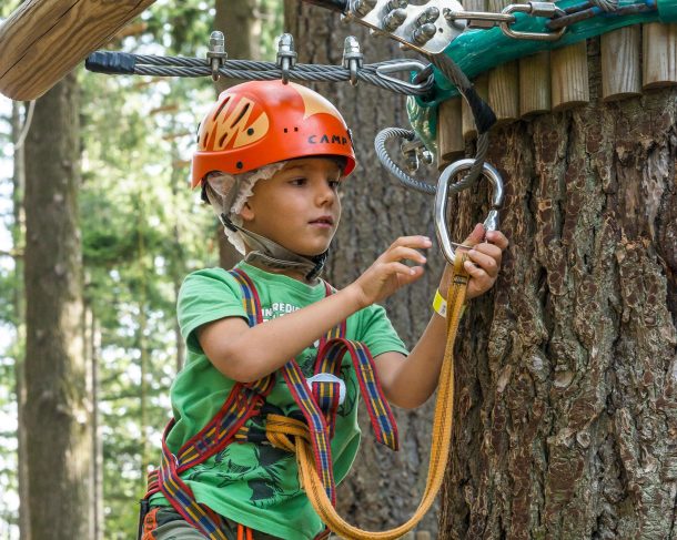 Bambino su percorso avventura con moschettone di sicurezza